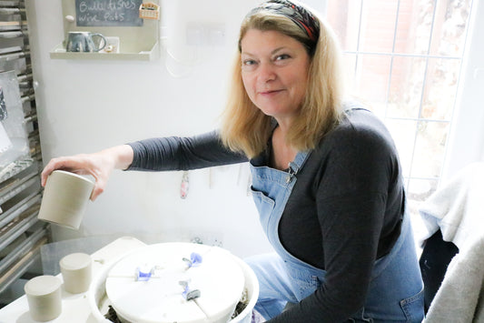 Potter at her wheel, lifting the pot and putting it on the side